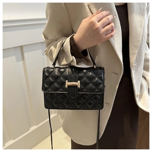 Detail showing the classic black quilted texture and golden rectangular buckle on the bag