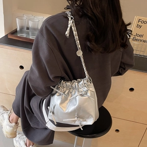 Sac seau argenté métallisé avec nœuds et bandoulière chaîne porté à l'épaule