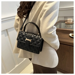 Detail view of quilted black leather bag featuring a gold H-shaped clasp and handle