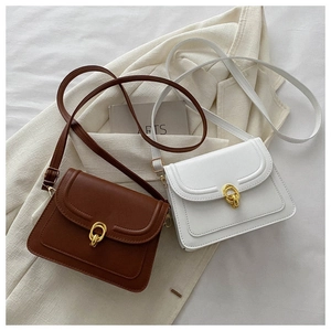 Flat lay detail of minimalist crossbody flap bags in brown and white with gold metal hardware