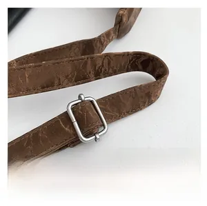 Detail of dark brown wrinkled texture shoulder strap with silver square metal buckle