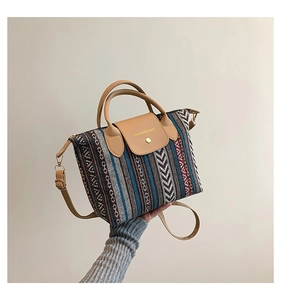 Detail of the woven geometric pattern and leather handle on a colorful ethnic tote bag
