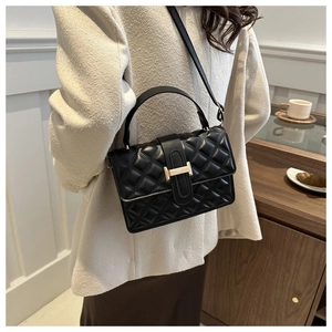 Detail of classic black quilted shoulder bag featuring elegant golden H-shaped metal clasp
