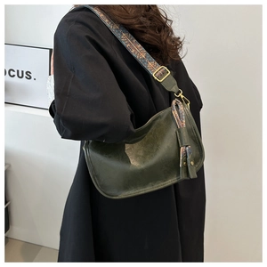 Détail du sac rétro vert foncé avec bandoulière jacquard ethnique et pompon décoratif