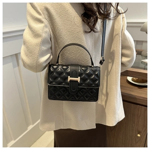Detailed close-up of the quilted diamond pattern and golden H-shaped buckle on black leather bag