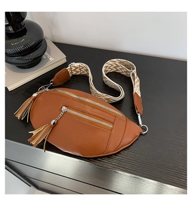 Détail du sac banane en cuir marron avec fermetures éclair argentées et pompons en cuir