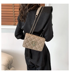Detail of khaki quilted crossbody bag with heart-shaped golden buckle and chain strap