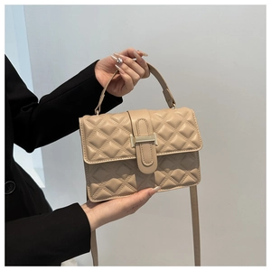 Detail of beige quilted faux leather bag with elegant golden square metal clasp and top handle