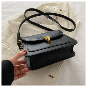 Detail shot of black leather handbag featuring a gold buckle and fine stitching