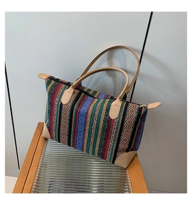 Detail of bohemian tote bag showing colorful woven stripes and light camel leather handles