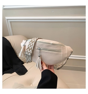 Détail du sac de poitrine en similicuir blanc cassé avec pompons et bandoulière tissée