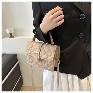 Detail of light khaki quilted crossbody bag with gold metal buckle and hand strap
