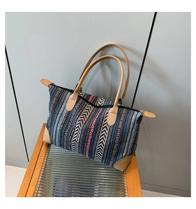 Detail of ethnic geometric woven tote bag with brown faux leather handles and trim