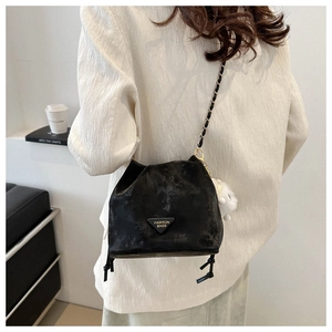 Detail shot of black retro bucket bag with gold chain strap and plush ball charm