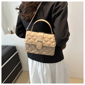 Detail of beige quilted crossbody bag with golden H buckle shown on a model