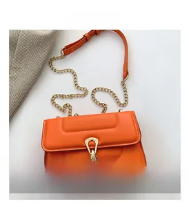 Vue détaillée du sac bandoulière orange vif avec fermoir en U doré et bandoulière chaîne