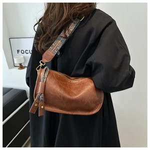 Détail du sac à main en cuir marron avec bandoulière brodée bohème et pendentif à franges