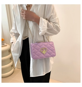 Close-up of lilac quilted crossbody bag with a gold heart clasp and chain strap
