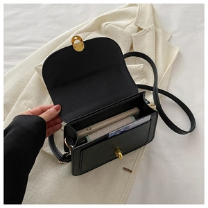 Detail view showing interior space with gold metal rotating lock on black crossbody bag