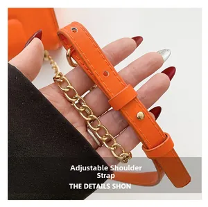 Détail de la bandoulière réglable en cuir orange avec chaîne en métal doré