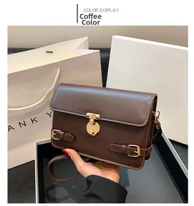Detail of dark brown leather square shoulder bag with retro gold buckle and straps