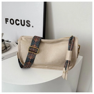 Détail du sac cylindre crème en similicuir texturé avec bandoulière bohème colorée