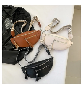 Détail de trois sacs bandoulière en simili cuir marron, beige et noir avec glands