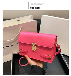 Detail of rose red leather crossbody bag with golden circular metal twist lock and strap