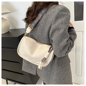 Détail du sac bandoulière crème avec sangle brodée bohème porté par un mannequin chic