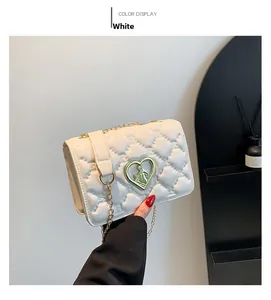 Detailed view of white quilted crossbody bag with golden heart-shaped relief buckle