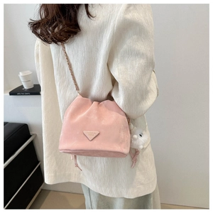 Detailed macro view of pink suede bucket bag with gold chain and soft fur ball charm