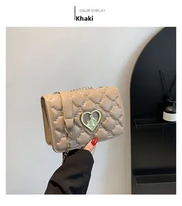Detail of khaki quilted crossbody bag with heart-shaped golden buckle and chain strap