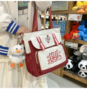 Close-up of a red and white canvas tote bag with a cute white duck plush keychain