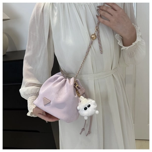 Detail of light purple drawstring bucket bag with gold chain and plush monster charm