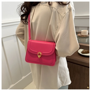 Detail of rose pink square shoulder bag with gold clasp shown in a modern interior setting