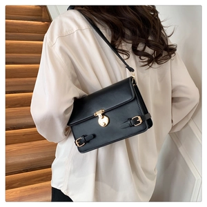 Detailed back view of a black leather crossbody bag with golden hardware on a model