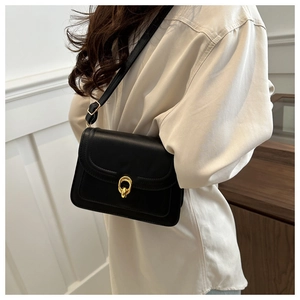 Detailed shot of a black matte leather crossbody bag featuring gold double-ring hardware