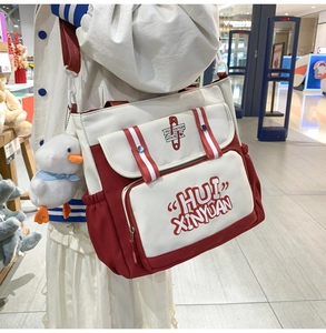 Detail of red and white canvas messenger bag with a cute white duck plush keychain