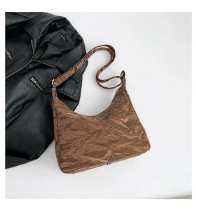 Detail of a brown pleated hobo shoulder bag with a unique textured crescent shape