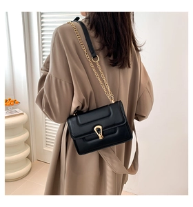 Détail du sac à main en cuir noir avec bandoulière chaîne dorée et fermoir en métal en U