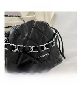 Detail view of black quilted bucket bag with silver chain handle and drawstring closure