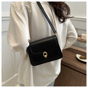 Detail view of the sleek black leather crossbody bag with elegant gold metal ring buckle