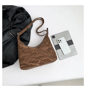 Detail of the brown crinkled faux leather texture and moon-shaped design of this tote bag