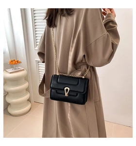 Détail d'un sac à bandoulière en cuir noir matelassé avec boucle en U dorée et chaîne