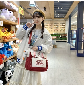 Detail of red and white messenger bag with cute duck pendant in lifestyle setting