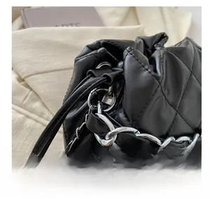 Detailed macro view of black quilted bucket bag with silver metal chain and drawstring