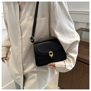 Detail of elegant black PU leather crossbody bag with golden interlocking circle lock