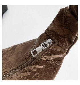 Detail of brown pleated handbag showing textured surface and silver metal zipper