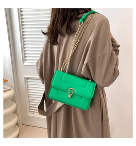 Détail d'un sac à main en cuir PU vert vif avec chaîne dorée sur un trench-coat kaki