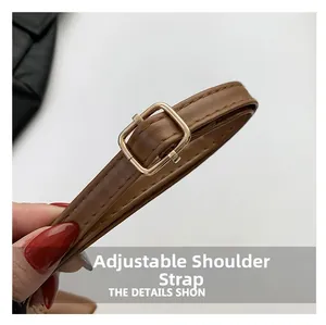 Detailed view of the adjustable brown faux leather shoulder strap with gold metal buckle